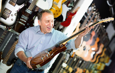 Adult guitarist is playing on electric guitar in music store.