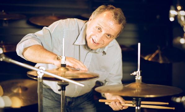 Adult man is choosing drum kit in music store.