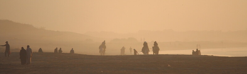 Spaziergänger und Reiter am abendlichen Strand von Essaouira / Marokko