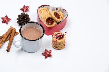 Cup of hot chocolate with cinnamon sticks, christmas cookies with jam in heart shaped red box on white background. Christmas decoration.