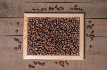 Coffee beans in a wooden frame on a wooden background top view