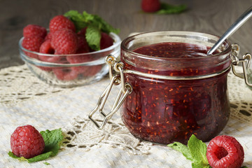 Raspberry jam in a glass jar with fresh raspberry berries