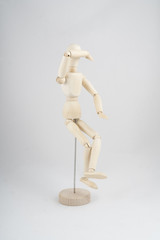 a wooden mannequin in sitting position	