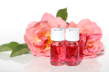 Cosmetic rose serie. Serum for  skin with rose extract. pink serum in glass ampoules  and fresh rose flowers on a white background. Organic Natural Cosmetics Concept