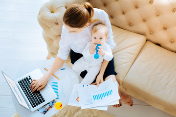 Busy businesswoman sitting with a funny baby