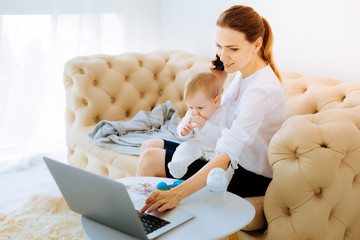 Pleasant woman working on the laptop while having a talk