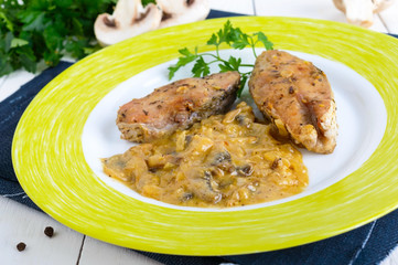 Roasted carp steaks with mushroom sauce on a plate on a white wooden background. Top view. Dish from the river fish.