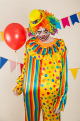 a terrible clown. Halloween. A crazy clown and a red balloon. Childish fear
