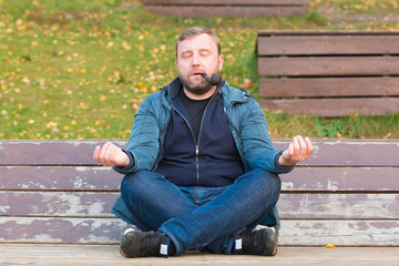 Fototapeta premium Young man smoking tobacco pipe in autumn park