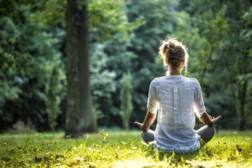 Selbstklebende Fototapete Yogaschule Frau meditiert und praktiziert Yoga im Wald