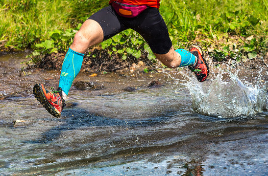 Dynamic Man Running In The Mountain, Jumping Over A Creek