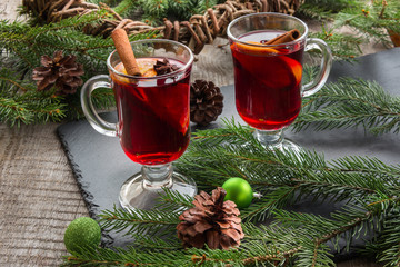 Christmas hot mulled wine with cinnamon, orange and christmas tree on black slate dish.
