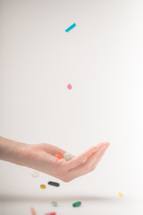 female hand catching falling pills