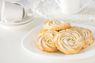 Round shortbread cookies rose form with icing on plate. White background. Close up. Selective focus.