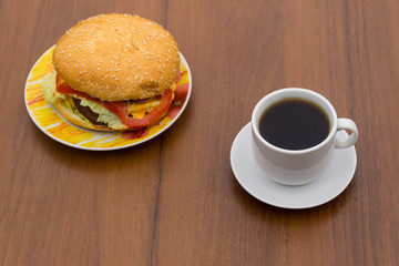 Delicious hamburger and cup of coffee on wooden table