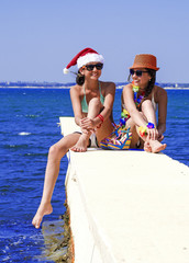 Portrait beautiful women, has haired long hair, blue and white bikini, sunglasses, slim body, happy smile face, red Christmas hat. Tropical hot sea.