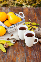 tea with lemon, honey, oranges, autumn leaves on woodenbackground