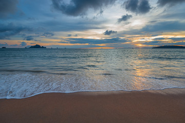 Fototapeta na wymiar beautiful waves and sandy shore, on the horizon the sun sets over the mountains