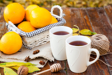 tea with lemon, honey, oranges, autumn leaves on woodenbackground