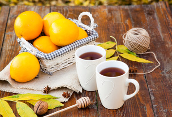 tea with lemon, honey, oranges, autumn leaves on woodenbackground