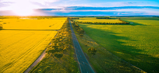 Aerial panorama of rural road passing through agricultural land in Australian countryside at sunset