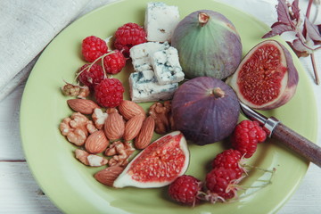Serving the table, fresh figs, fruits, berries, raspberries, cheese, nuts almonds on a white wooden background