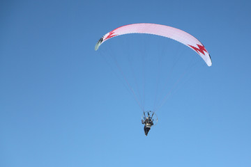 Man with a parachute and a motor flying in the blue sky