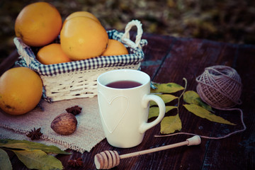 tea with lemon, honey, oranges, autumn leaves on woodenbackground