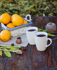 tea with lemon, honey, oranges, autumn leaves on woodenbackground