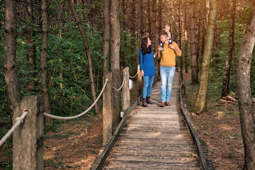 A young couple walks in the woods with a little boy