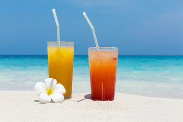 Cocktails in glass on white sandy beach