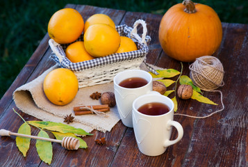 tea with lemon, honey, oranges, autumn leaves on woodenbackground