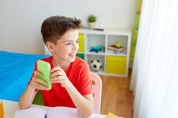 student boy with smartphone distracting from study