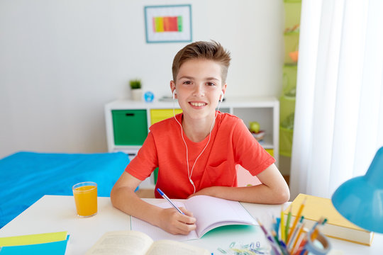 happy student boy writing to notebook at home