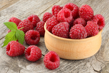 ripe raspberries in wooden bowl on old wooden table background