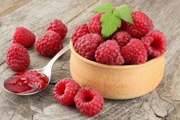 ripe raspberries in wooden bowl on old wooden table background