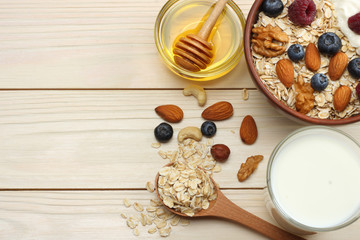 healthy breakfast. oatmeal, blueberries, raspberries, honey and nuts on white wooden table. Top view with copy space