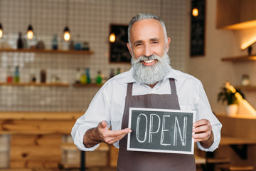 senior worker holding open chalkboard