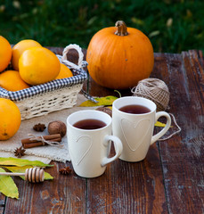 tea with lemon, honey, oranges, autumn leaves on woodenbackground