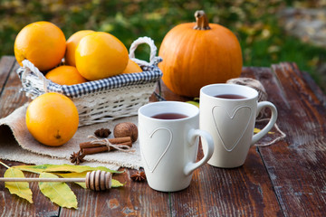 Obraz na płótnie Canvas tea with lemon, honey, oranges, autumn leaves on woodenbackground