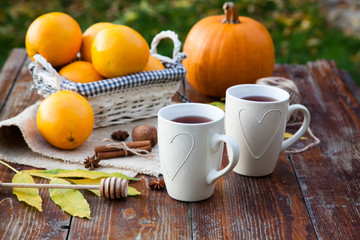 tea with lemon, honey, oranges, autumn leaves on woodenbackground