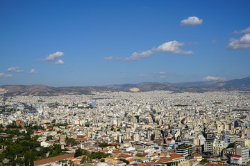 View of Athens city from Acropolis showing white buildings architecture, mountain, trees, blue sky and white cloud background