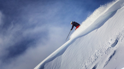 freeride skier going down through steep terrain