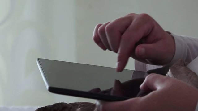Close up of female hand using digital tablet for social network activities in bedroom, woman with portable touchscreen computer device in bed.
