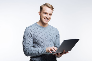 Handsome man in grey sweater working on laptop
