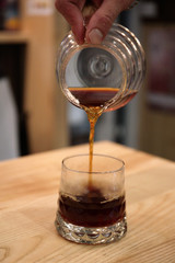 Barista pours a coffin into the glass cup. He serves a drink.