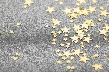 Fototapeta premium Gold star confetti on a silver glitter background. festive holiday background