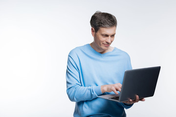 Pleasant middle-aged man working on laptop