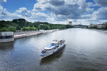 Fototapeta na wymiar Pushkinskiy (Andreevsky) pedestrian bridge across the Moscow River. Touristic boat