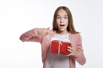 Fototapeta premium Charming teenage girl pointing at gift box with her finger